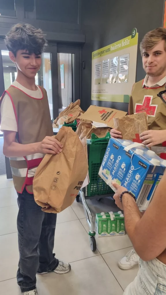 jovens-voluntários-da-cruz-vermelha-entregam-saco-com-alimentos-a-cliente-em-supermercado